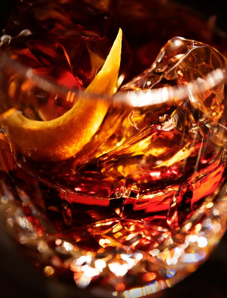 close up of whiskey glass with ice and ring of orange peel