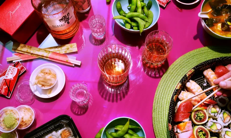 Hibiki Suntory Whiskey cocktailsOverhead view of a pink table with glasses of whiskey, edamame, and small snacks.