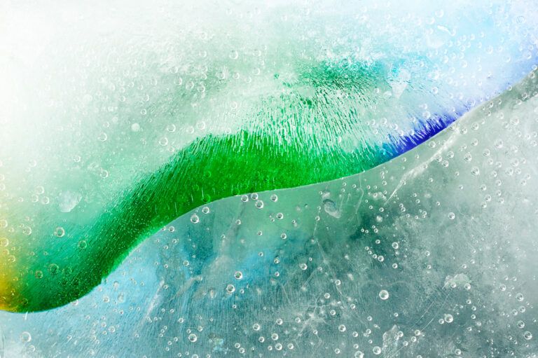 Close-up of green and blue liquids mixing with fine air bubble