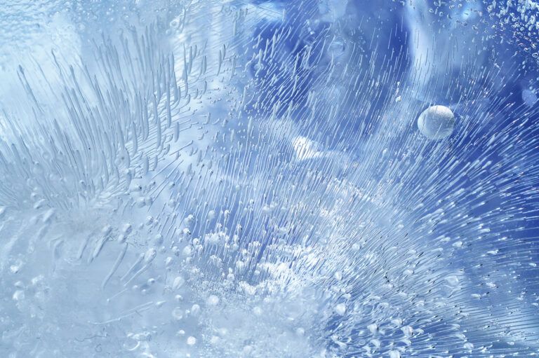 Macro texture of cracked, frozen blue ice with crystalline patterns.