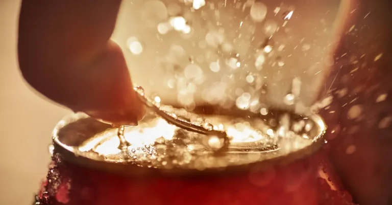 Macro shot of a single water droplet hitting a liquid surface with golden light.