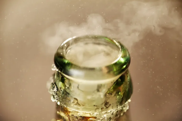 Close-up of the rim of a glass bottle with condensation and mist rising from the opening