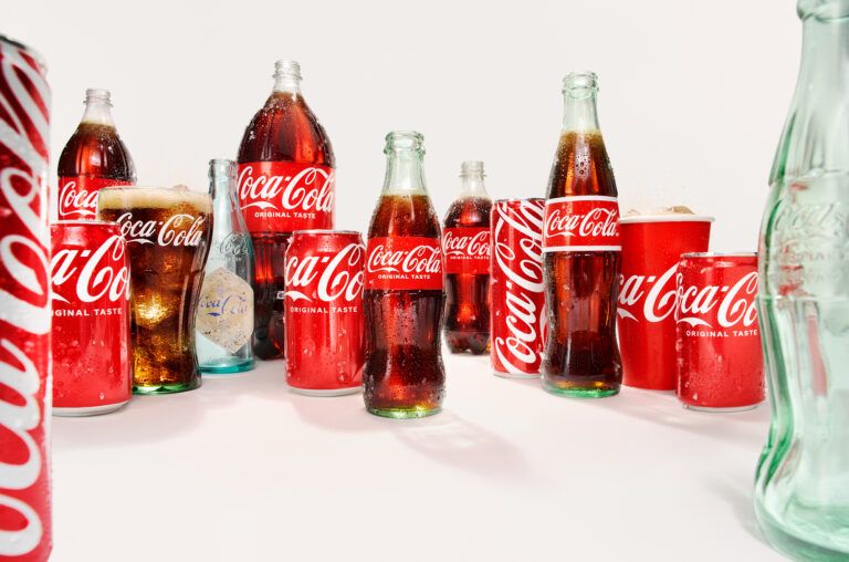 A collection of vintage and modern Coca-Cola glass bottles and cans on a white background.