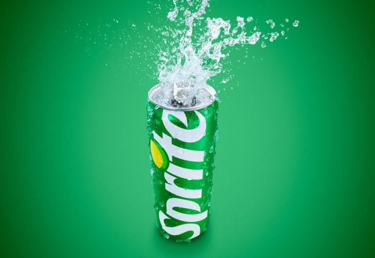 A green Sprite can centered in a refreshing splash of water against a light green background.